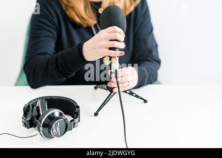 Frauenmikrofon mit Kopfhörern auf dem Schreibtisch Stockfoto