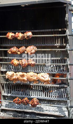 Riesige Spucke mit gebratenen Hühnern und Schweinshaxe beim Kochen im Restaurant, das auf Fleischgerichte spezialisiert ist Stockfoto