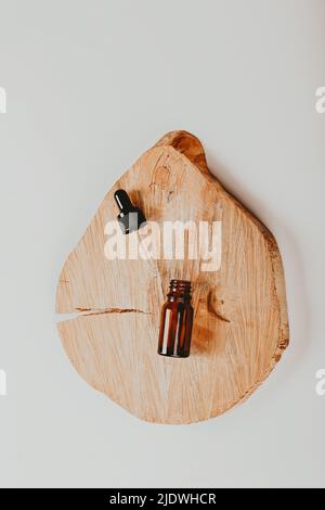 Abstraktes Kosmetiklabor. Flaschen aus dunklem Bernsteinglas auf einem hölzernen Podium. Naturkosmetik. Flach, Draufsicht Stockfoto