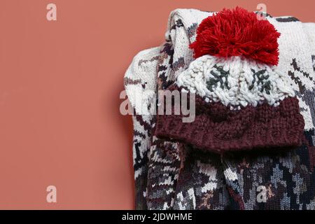 Set warmer Herbstkleidung auf beigem Hintergrund, Draufsicht. Strickpullover und Wollmütze. Flacher Stil und Platz für Text Stockfoto