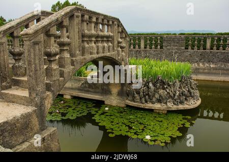 Die Brücke zur Insel im Teich des Ferrari-Gartens im Dorf Stanjel, in der Gemeinde Komen in der Region Primorska, Westslowenien Stockfoto