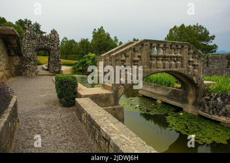 Die Brücke zur Insel im Teich des Ferrari-Gartens im Dorf Stanjel, in der Gemeinde Komen in der Region Primorska, Westslowenien Stockfoto