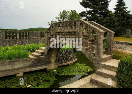 Die Brücke zur Insel im Teich des Ferrari-Gartens im Dorf Stanjel, in der Gemeinde Komen in der Region Primorska, Westslowenien Stockfoto