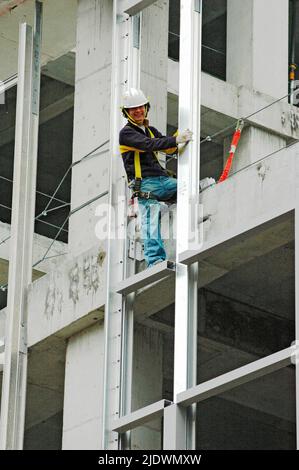 Hochhaus-Konstruktion aus Eisen und Stahl und Zement mit Arbeitern in Sicherheit Ausrüstung Stockfoto