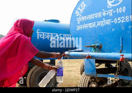 INDIEN, Uttar Pradesh, Bundelkhand, Mahoba, Wasserknappheit, Frauen in rosa Saree am blauen Wasserbehälter, der Plastikflasche mit Trinkwasser füllt, während einer Kundgebung der Frauenbewegung Gulabi Gang Stockfoto