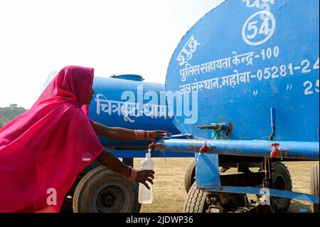 INDIEN, Uttar Pradesh, Bundelkhand, Mahoba, Wasserknappheit, Frauen in rosa Saree am blauen Wasserbehälter, der Plastikflasche mit Trinkwasser füllt, während einer Kundgebung der Frauenbewegung Gulabi Gang Stockfoto