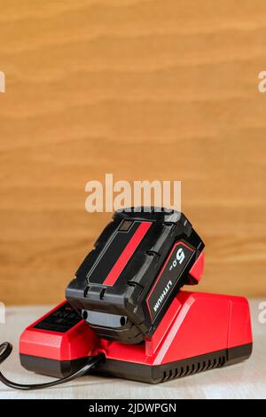 Der Vorgang, bei dem eine Lithiumbatterie von einem kabellosen Bauwerkzeug geladen wird. Der Akku des Schraubendrehers wird im Ladegerät geladen Stockfoto