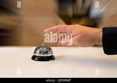 Die Hand eines Mannes wird eine alte Hotelglocke mit Bewegungsunschärfe-Effekt verwenden Stockfoto