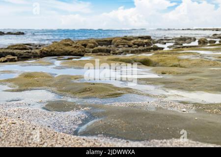 Abstraktes Bild, selektive Fokusebene aus Sand und Felsen und das Meer im Hintergrund nicht fokussiert. Stockfoto