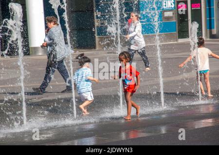 Wien, Österreich - 06.13.2022: Kinder tummeln sich in der Sommerhitze in den Jets des Stadtbrunnens Stockfoto