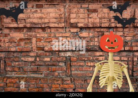 Halloween Dekorationen Skelett mit Fledermäusen auf alten roten Backstein Hintergrund. Halloween-Konzept. Flach liegend, Draufsicht, Kopierbereich Stockfoto