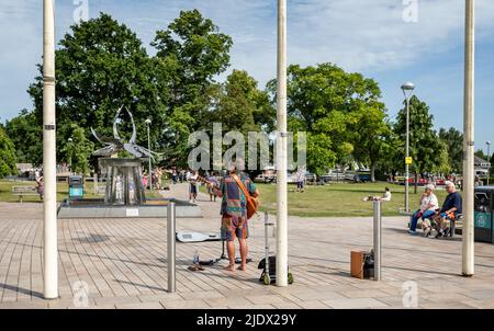 Junger Straßenmusiker, der am 16. Juni 2022 vor dem Swan Fountain in Stratford-upon-Avon, Warwickshire, Großbritannien, Gitarre spielt Stockfoto