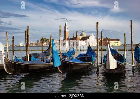 Venedig, Weitwinkelaufnahme von Gondeln oder Gondeln und Wahrzeichen der Kirche San Giorgio Maggiore vor dem dramatischen blauen Himmel. Italien, Europa. Stockfoto