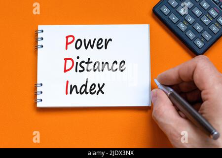 PDI-Leistungsindex. Concept Words PDI Power distance Index auf weißer Note auf einem schönen orangefarbenen Hintergrund. Geschäftsmann Hand. Geschäftliche PDI Stockfoto