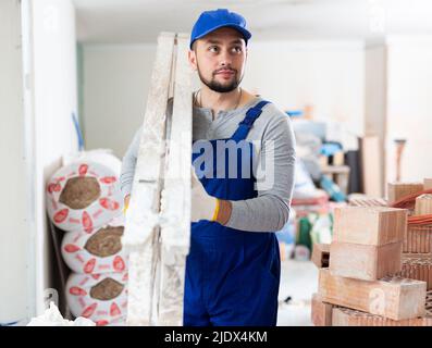 Bauarbeiter, der Leiter bei der Renovierung des Objekts trägt Stockfoto