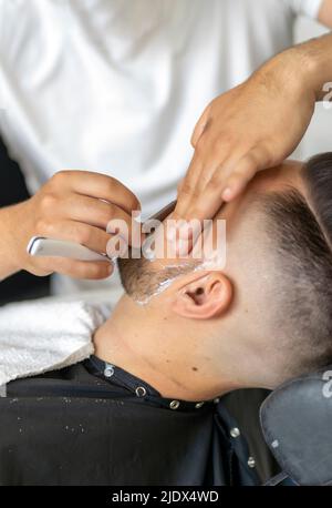 Professioneller Friseur, der einen Kunden rasieren kann Stockfoto