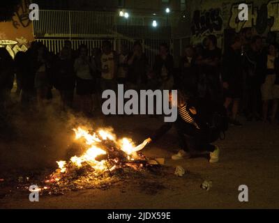 Madrid, Spanien. 23.. Juni 2022. Eine Frau, die während der Heiligabend in Madrid ein Stück Papier mit Wünschen in ein Lagerfeuer warf. Hunderte von Menschen feierten die Sommersonnenwende, indem sie Lagerfeuer im Cornisa Park während der Johannisnacht in Madrid anzünden. Die Leute verbrannten früher Papierstücke, die mit Dingen geschrieben waren, die man vergessen sollte, und hüpften sich über die Lagerfeuer, um Wünsche zu erfüllen. © Valentin Sama-Rojo/Alamy Live News. Stockfoto