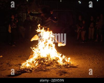 Madrid, Spanien. 23.. Juni 2022. Eine Frau, die während der Johanniternacht in Madrid durch das Feuer eines Lagerfeuers springt. Hunderte von Menschen feierten die Sommersonnenwende, indem sie Lagerfeuer im Cornisa Park während der Johannisnacht in Madrid anzünden. Die Leute verbrannten früher Papierstücke, die mit Dingen geschrieben waren, die man vergessen sollte, und hüpften sich über die Lagerfeuer, um Wünsche zu erfüllen. © Valentin Sama-Rojo/Alamy Live News. Stockfoto