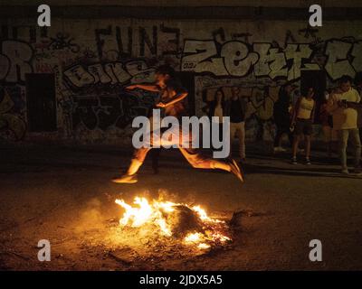 Madrid, Spanien. 23.. Juni 2022. Eine Frau, die während des Johanniterabends in Madrid auf das Feuer springt. Hunderte von Menschen feierten die Sommersonnenwende, indem sie Lagerfeuer im Cornisa Park während der Johannisnacht in Madrid anzünden. Die Leute verbrannten früher Papierstücke, die mit Dingen geschrieben waren, die man vergessen sollte, und hüpften sich über die Lagerfeuer, um Wünsche zu erfüllen. © Valentin Sama-Rojo/Alamy Live News. Stockfoto