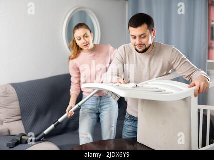 Junges Paar, das Tisch im Wohnzimmer putzt Stockfoto