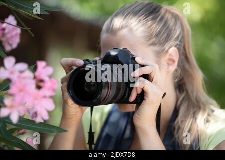 Schöne Frau, die in einem Frühlingsgarten Tulpen fotografiert Stockfoto