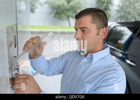 Person, die Münzen bezahlt, um automatische Selbstbedienung Auto Stockfoto