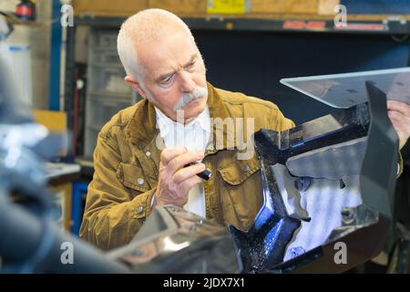 Älterer Mann, der das Motorrad inspiziert Stockfoto