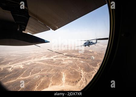 Ein 332d Air Expeditionary Wing HH-60G Pave Hawk Hubschrauber erhält Treibstoff von einem HC-130J Combat King II Flugzeug, das ebenfalls dem 332d AEW zugewiesen wurde, in Südwestasien, 12. Juni 2022. Die primäre Aufgabe des Pave Hawk besteht darin, Tag- oder Nachteinsätze zur Wiederherstellung von Personal in feindlichen Umgebungen durchzuführen, um isoliertes Personal während eines Konflikts zu erholen. Die HH-60G ist auch mit militärischen Operationen außer Konflikten beauftragt, einschließlich zivile Such- und Rettungsmaßnahmen, medizinische Evakuierung, Katastrophenhilfe, humanitäre Hilfe, Sicherheitskooperation/Luftverkehrsberatung, NASA Raumfahrt Unterstützung und Rettung c Stockfoto