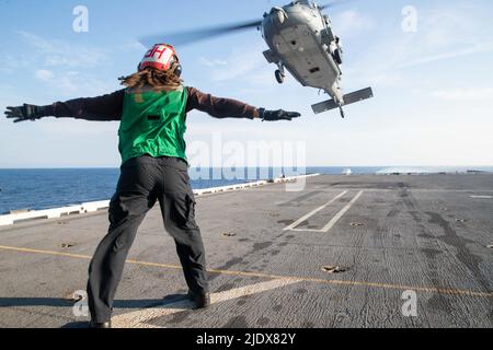 Flugelektroniktechnikerin 3. Klasse Gabriella Corbett aus Willingboro, New Jersey, die den „Tridenten“ des Helicopter Sea Combat Squadron (HSC) 9 zugewiesen wurde, meldet als Landeanstellungsingenieurin einen MH-60s Nighthawk-Hubschrauber auf dem Flugdeck der USS Gerald R. Ford (CVN 78), 18. Juni 2022. Ford ist im Gange im Atlantik und führt die Qualifikation des Chief of Naval Air Training Command (CNATRA)-Trägers durch. (USA Navy Foto von Mass Communication Specialist Seaman Apprentice Daniel Perez) Stockfoto