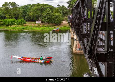 Langboot von der berühmten Brücke auf dem Fluss Kwai aus gesehen. Das rote Boot ist auf dem Kwai Fluss ist nicht unter der Brücke, sondern zur Seite. Stockfoto