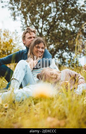 Glückliche Mutter und Vater mit Tochter auf der Wiese Stockfoto
