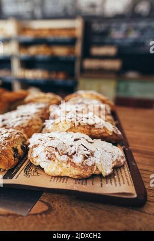 Mandelcroissants mit Puderzucker auf Tablett in der Bäckerei angeordnet Stockfoto