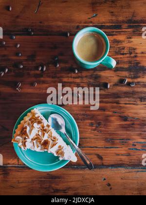 Kuchenscheibe und Kaffee mit verstreuten gerösteten Bohnen auf dem Tisch Stockfoto