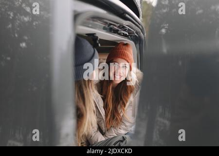 Glückliche Rotschopf Frau trägt Strickmütze Blick auf Freund im Wohnmobil sitzen Stockfoto