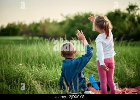 Bruder und Schwester winken mit den Händen auf dem Feld Stockfoto