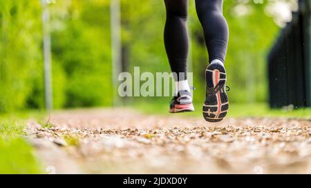 Junge Frau trägt Sportschuhe beim Joggen im Park Stockfoto