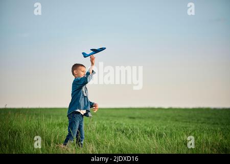 Junge werfen Flugzeug Spielzeug im Feld am Wochenende Stockfoto