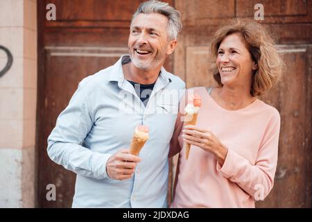 Fröhliches reifes Paar mit Eis vor der Tür Stockfoto