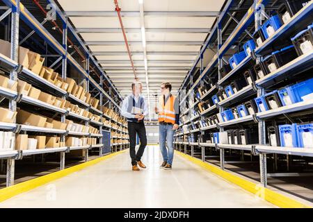 Manager und Mitarbeiter besprechen das Gehen im Gang im Lager Stockfoto