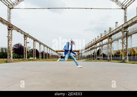 Junger Mann, der Luftgitarre spielt und auf Fußwegen springt Stockfoto