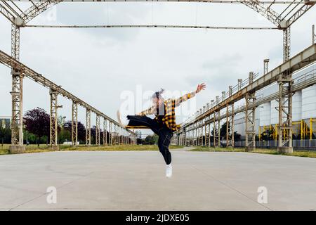 Glücklicher junger Mann, der auf dem Fußweg springt Stockfoto
