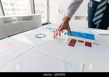 Hand eines Geschäftsmannes, der am Schreibtisch im Büro an Diagrammen und Grafiken arbeitet Stockfoto