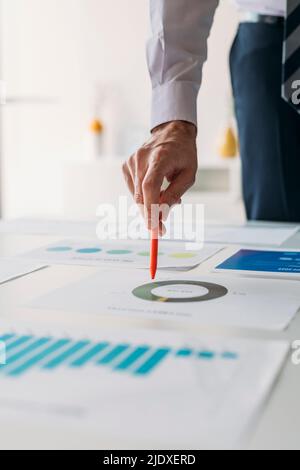 Hand des Geschäftsmannes mit Stift, der im Büro an Diagrammen und Diagrammen arbeitet Stockfoto