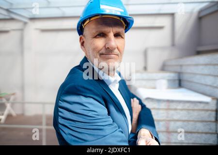 Geschäftsmann mit gekreuzten Armen auf der Baustelle Stockfoto