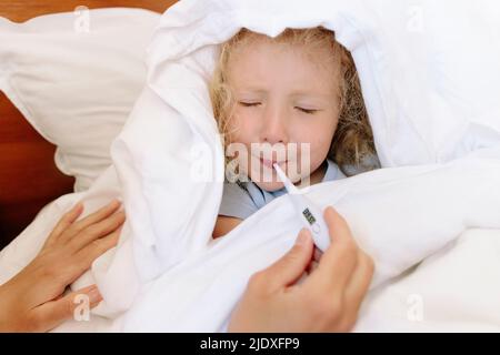 Kranke Tochter vermeiden, Thermometer von der Mutter im Schlafzimmer zu verwenden Stockfoto
