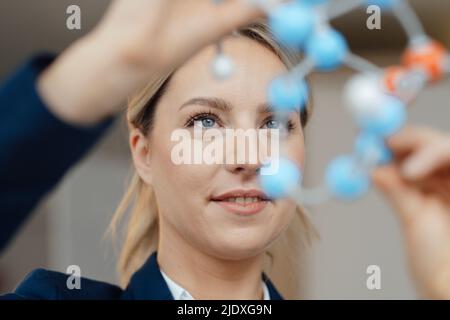 Lächelnde Geschäftsfrau, die im Büro das molekulare Modell untersucht Stockfoto