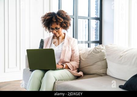 Junge Frau, die Arbeiten am Laptop im Büro Stockfoto