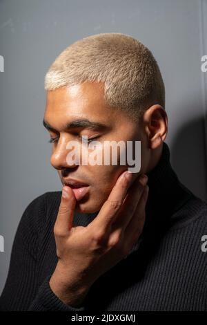 Junger Mann mit geschlossenen Augen vor grauem Hintergrund Stockfoto