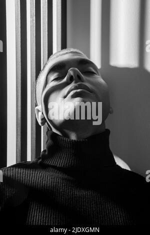 Junger Mann mit Rollkragen an der Wand gelehnt Stockfoto