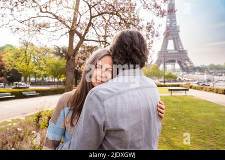 Lächelnde reife Frau umarmt ihren Freund vor dem Eiffelturm, Paris, Frankreich Stockfoto